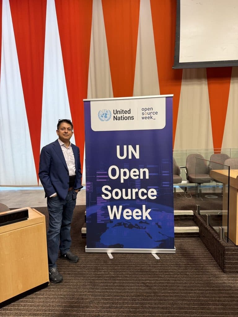Aruneesh Salhotra beside a UN Open Source Week banner at the United Nations